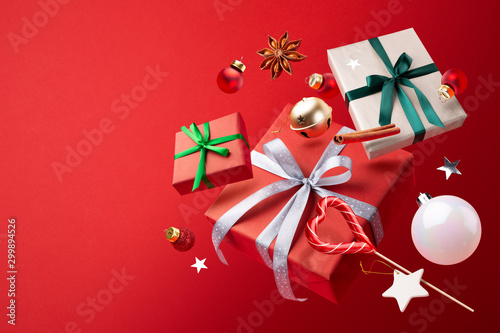 Happy New year magic concept. Christmas gifts, Lollipop, decorations and toys fly or fall in the air on a red background.