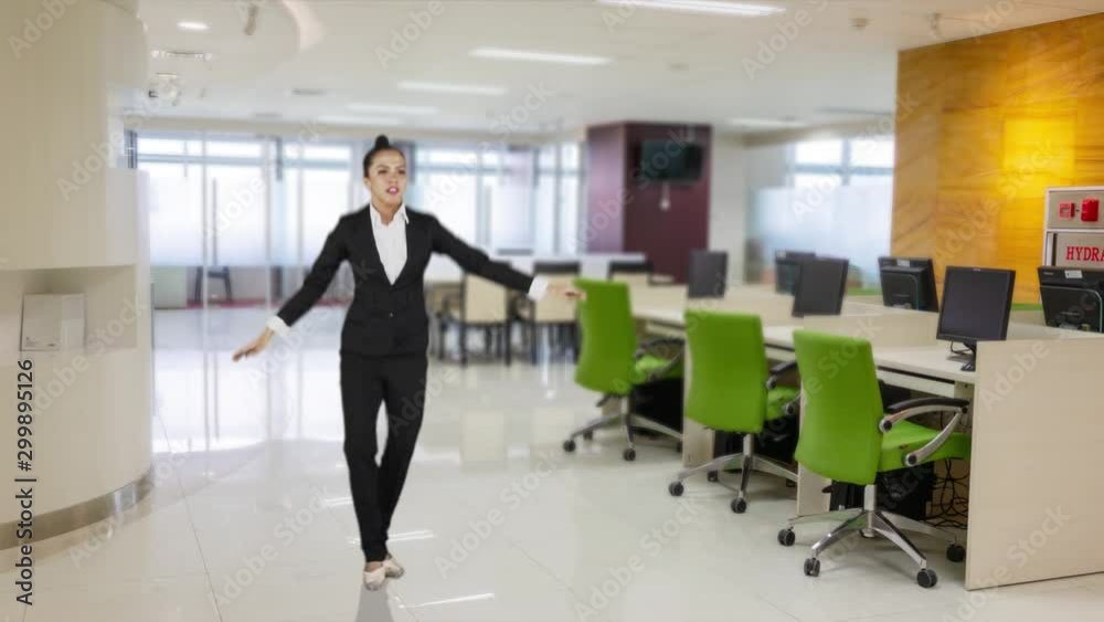 Slow motion of attractive businesswoman with ballet skill jumping in the office room while wearing formal suit Slow motion of attractive businesswoman with ballet skill jumping in the office room while wearing formal suit