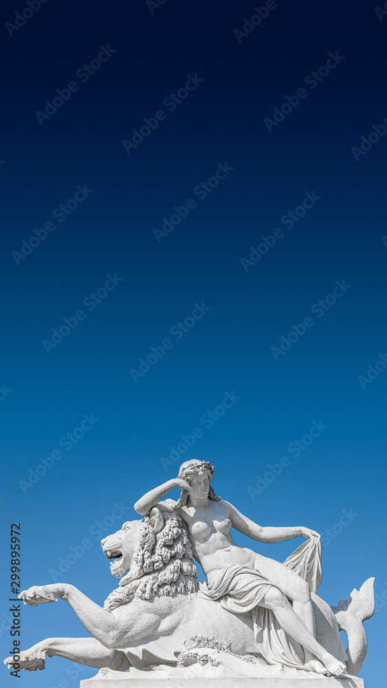 Obraz premium Old statue of sensual Renaissance Era woman laying on big lion at blue smooth background, Potsdam, Germany, details, closeup