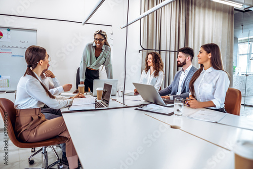 Communication and relaxed atmosphere during work.Young african business woman standing and talking with colleagues on the business presentation.