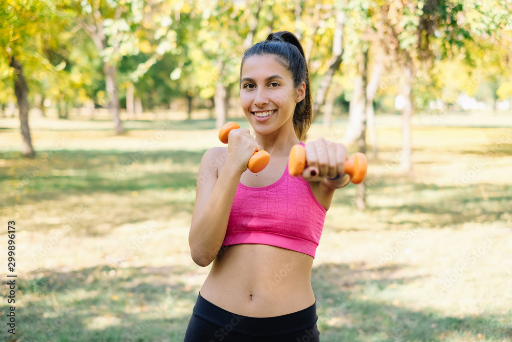 Fit girl doing dumbbells exercises while smiling Fit girl doing dumbbells exercises while smiling