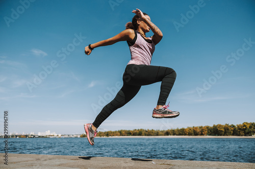Athletic Afro American lady running and jumping outdoors