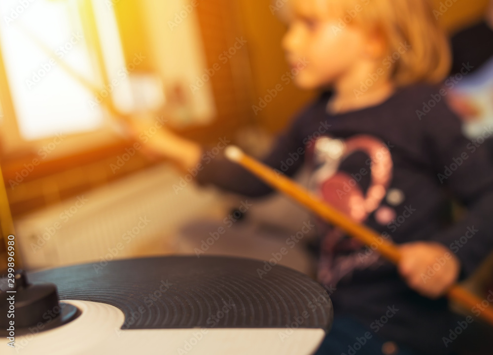 blurry image of drum and wooden drumsticks in hands. Girl learning and play drum set in music room, the concept of musical instrument. blurry image of drum and wooden drumsticks in hands. Girl learning and play drum set in music room, the concept of musical instrument.