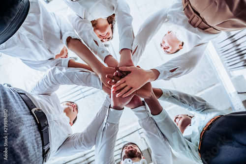 Young business people. The concept of unity and teamwork. Men and women joined in a circle with their hands together in a huddle to start working on an important project. Bottom view.