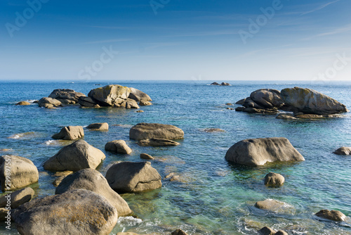 calm ocean and coast with large rocks and granite boulders in morning light