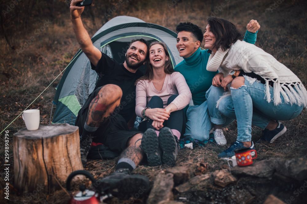 Young friends laughing, taking selfie,hanging out at campsite