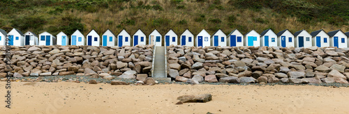 row of small wooden beach cottages on the rocky Normandy coast photo