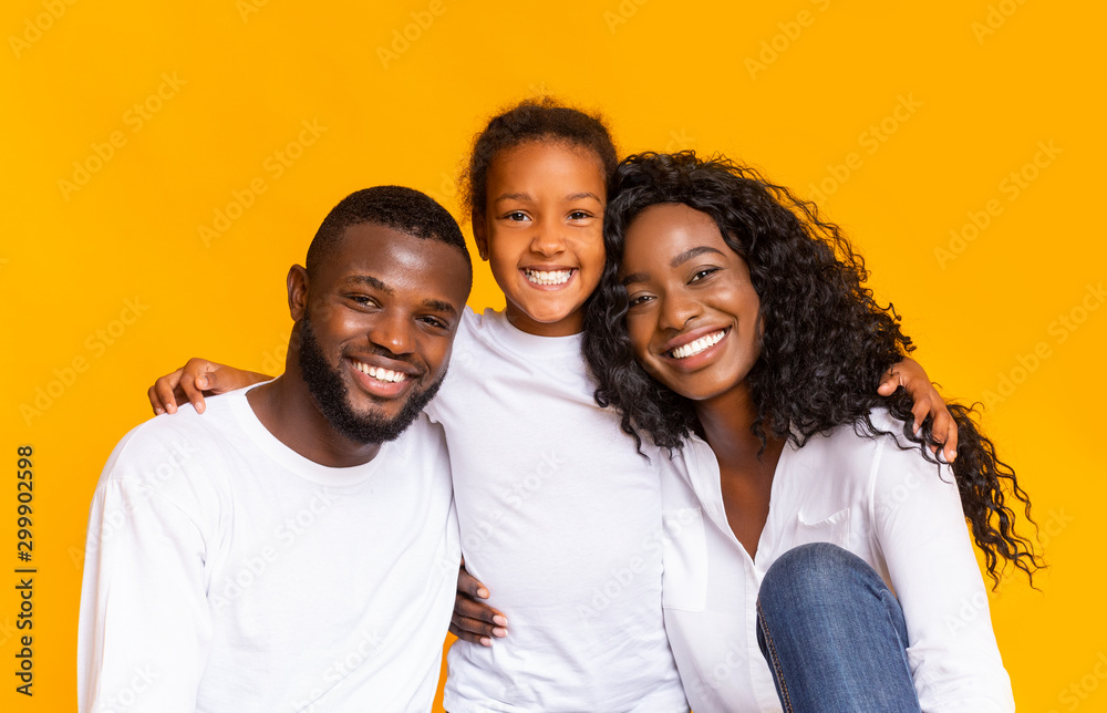 Happy black father, mother and daughter over yellow background