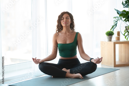 Attractive woman doing yoga and sitting in lotus position