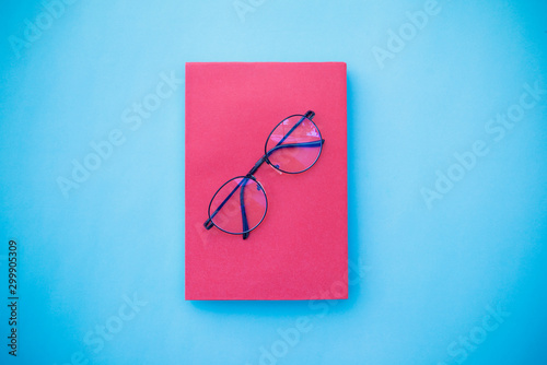 Glasses placed on pink book, Placed on blue background, Top view