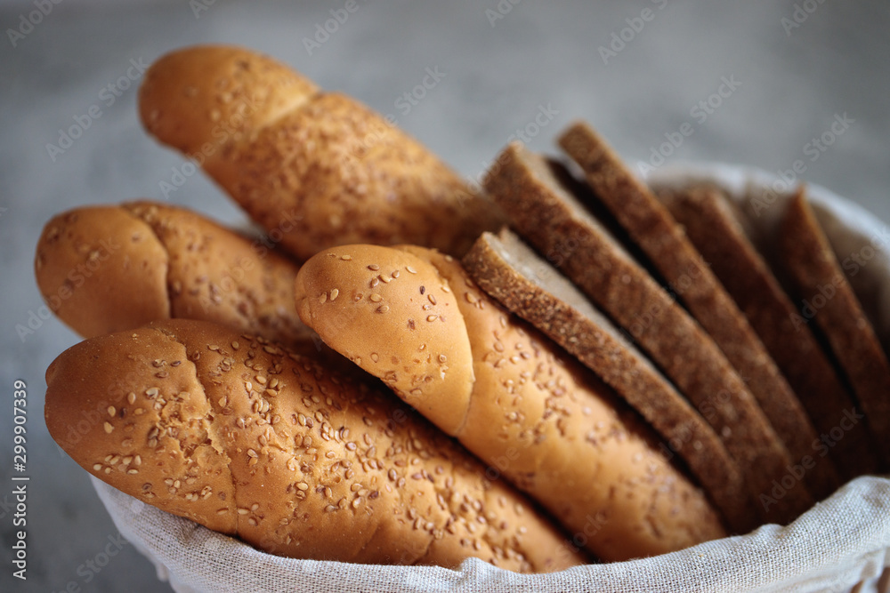 Fresh bread baguette with sesame seeds and slices of rye bread are in the breadbox on the table. Bakery. Flat lay. Close-up, minimalism.
