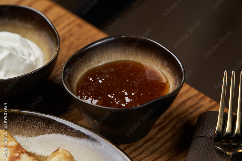 Homemade pancakes with jam, honey and sour cream bowls, close-up Homemade pancakes with jam, honey and sour cream bowls, close-up