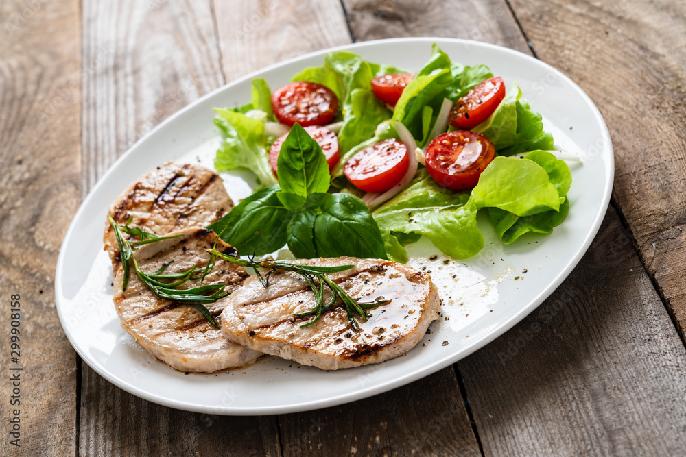 Grilled steaks with vegetable salad on white plate Grilled steaks with vegetable salad on white plate
