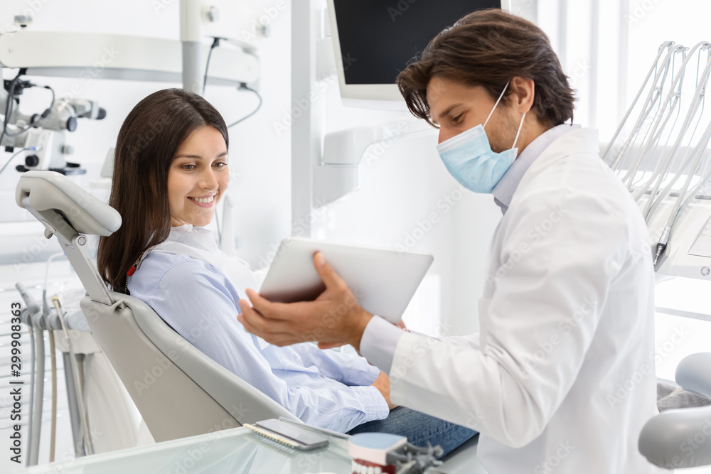 Fototapeta premium Dentist doctor showing patient result of treatment on digital tablet