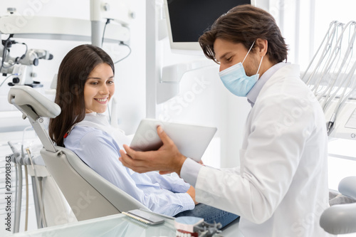Dentist doctor showing patient result of treatment on digital tablet