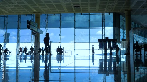 International airport with business people pulling trolley bags arriving and departing terminal tourists travelling and walking in lobby with big windows and blue sky 4k footage
