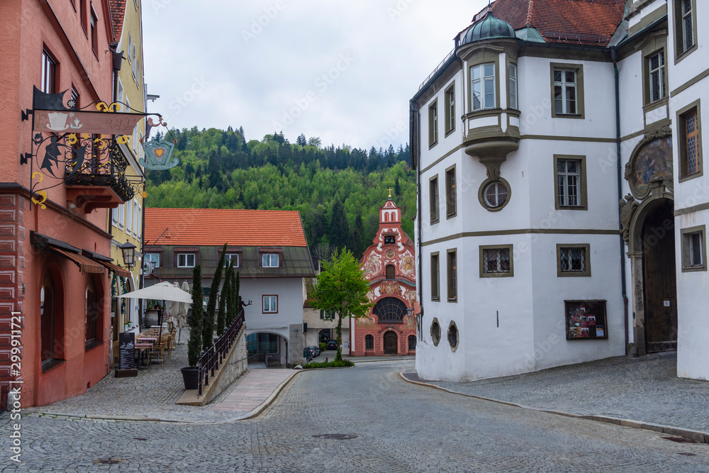 Street in the Gemany town Fussen with Benediktinerkloster St.Mang to the right and Church of the Holy Spirit in the middle Street in the Gemany town Fussen with Benediktinerkloster St.Mang to the right and Church of the Holy Spirit in the middle