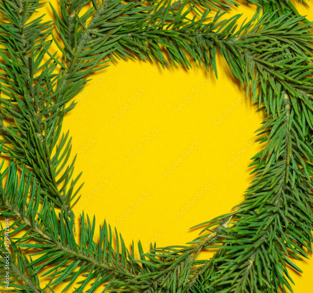 Circle frame made of fir branches on yellow background. Negative space. Merry christmas and happy new year concept