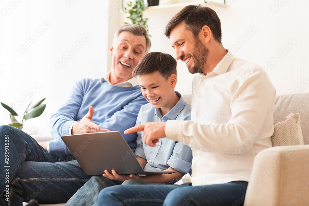 Boy Using Laptop Sitting Between Father And Grandfather On Couch Boy Using Laptop Sitting Between Father And Grandfather On Couch
