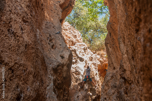 Male rock climber on challenging route in cave. Young man lead climbing in a beautiful grotto. The climber overcomes a difficult route. The athlete trains on a natural relief. Climbing in Spain.