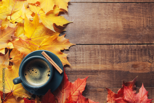 Grey cup of coffee, cinnamon, red and yellow maple leaves on dark wooden table. Autumn background concept. Fall menu, expresso, coffee shop, break, copy space, page
