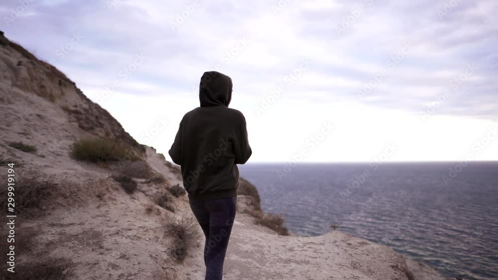 Jogging on a cliff by the ocean. Girl athlete in a warm sweatshirt is engaged in cardio exercise in nature. Fitness at dusk, healthy lifestyle Jogging on a cliff by the ocean. Girl athlete in a warm sweatshirt is engaged in cardio exercise in nature. Fitness at dusk, healthy lifestyle