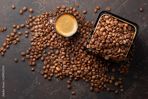 Coffee beans in metal jar and espresso in glass cup top view on dark background