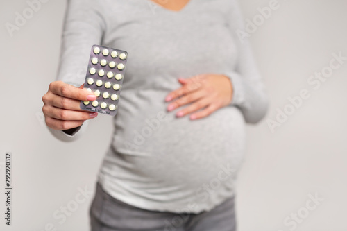 Unrecognizable Pregnant Girl Showing Pills Blister Pack Standing In Studio