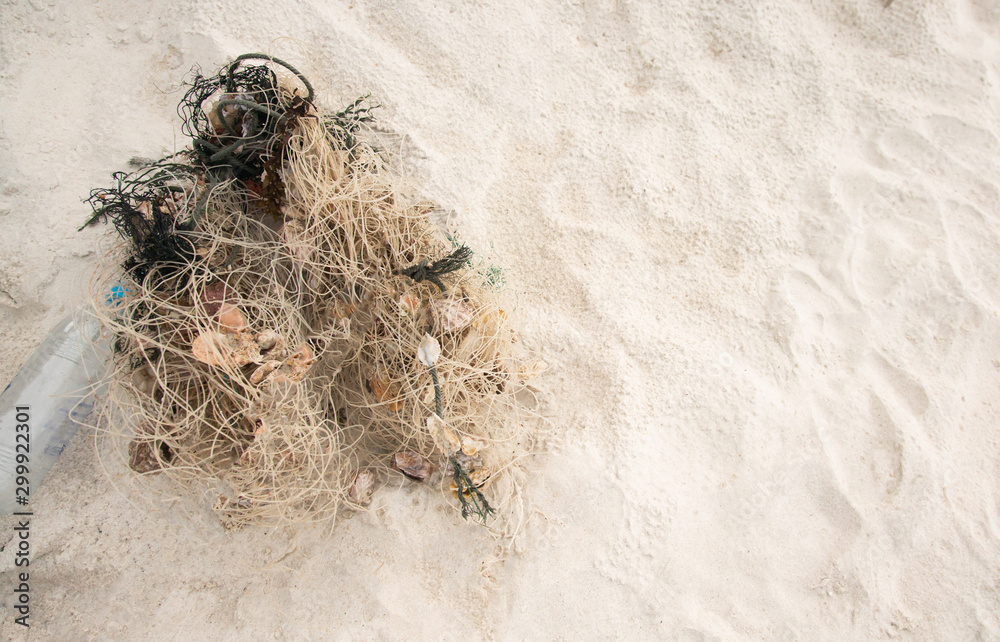 Obraz premium Garbage, sea fishing nets that have shells or shellfish and plastic bottles on the beach. Environment and marine pollution