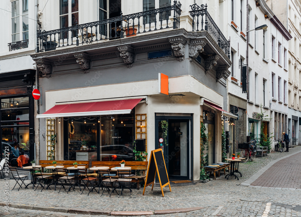 Naklejka premium Old street with tables of cafe in historic city center of Antwerpen (Antwerp), Belgium. Cozy cityscape of Antwerp. Architecture and landmark of Antwerpen
