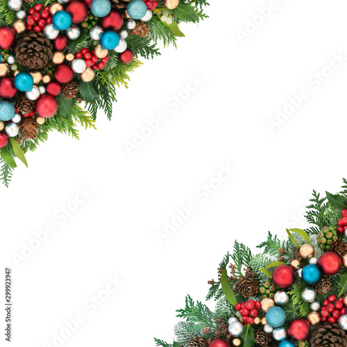Christmas & winter background border with red, blue and silver ball bauble decorations and winter flora with pine cones on white with copy space.