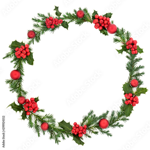 Christmas winter & new year juniper fir wreath with red baubles & loose red holly berries on white background with copy space. Traditional symbol for the festive season. Flat lay.