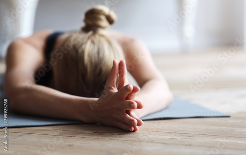 Fit girl laying face down on yoga mat, stretching