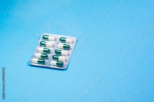 Medical pills in different colors on blue background.