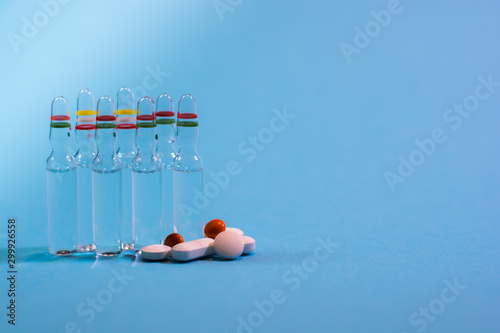 Medical ampules and pills on blue background