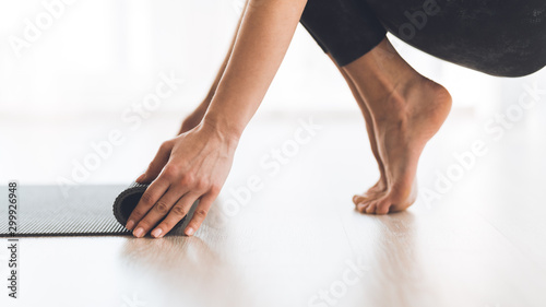Yoga concept. Woman rolling up yoga mat after training