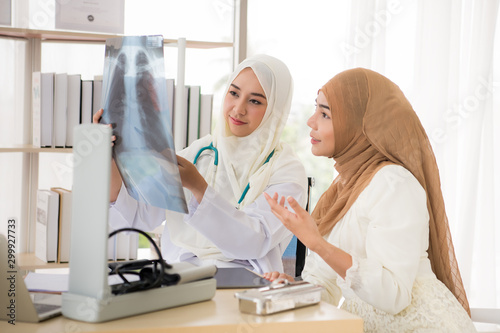 Muslim woman doctor talking to patient about x-ray result