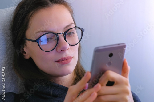 Woman in glasses watches serial on mobile phone. Face close-up