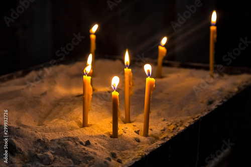 Prayer burning candles in a church on a dark background. Religious concept.