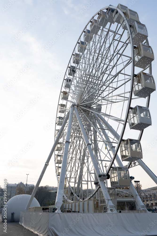Ferris wheel on a square in a big city on an autumn evening. Tourist attraction, entertainment and fun. Vertical