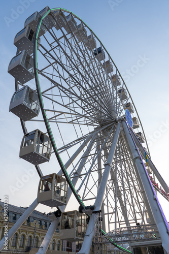Ferris wheel on a square in a big city on an autumn evening. Tourist attraction, entertainment. Vertical