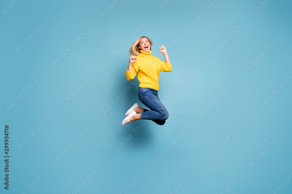 Full length profile photo of crazy lady jumping high celebrating winning free trip abroad rejoicing wear knitted yellow pullover jeans isolated blue color background