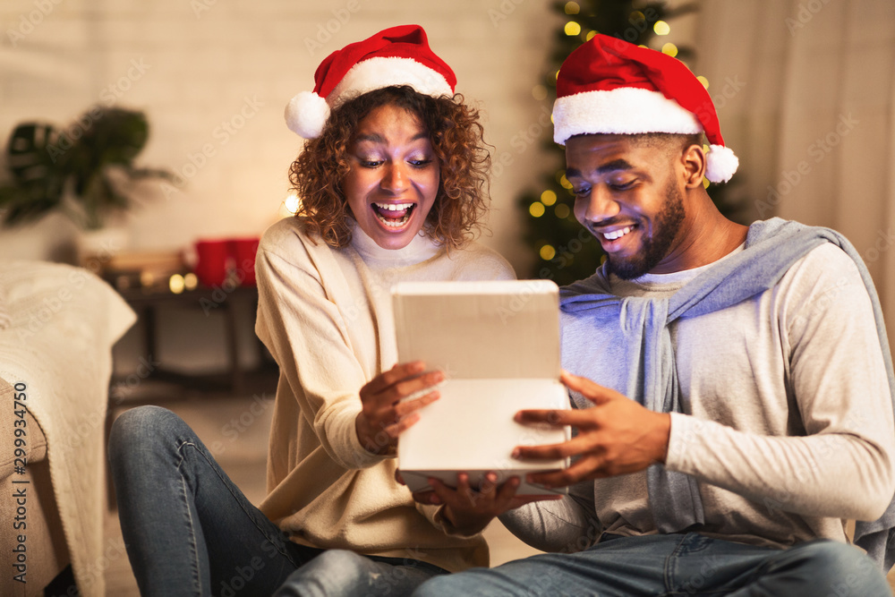 Overjoyed afro couple open xmas box and looking inside Overjoyed afro couple open xmas box and looking inside