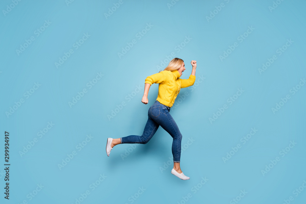 Obraz premium Full length photo of amazing blond lady jumping high rushing discount low prices shopping wear knitted yellow pullover jeans isolated blue color background