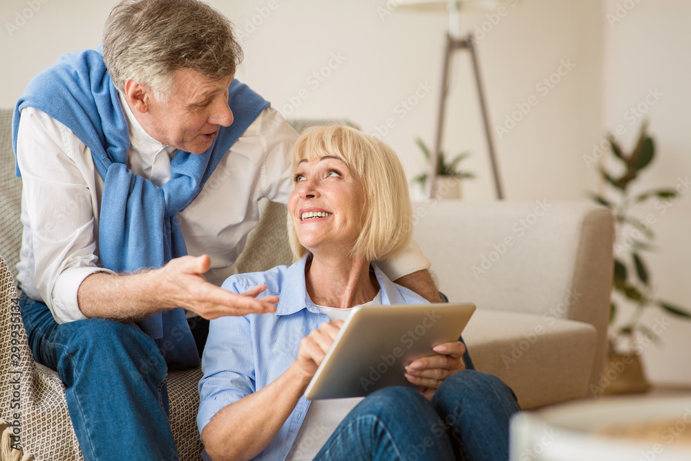 Obraz premium Modern senior spouses using digital tablet together