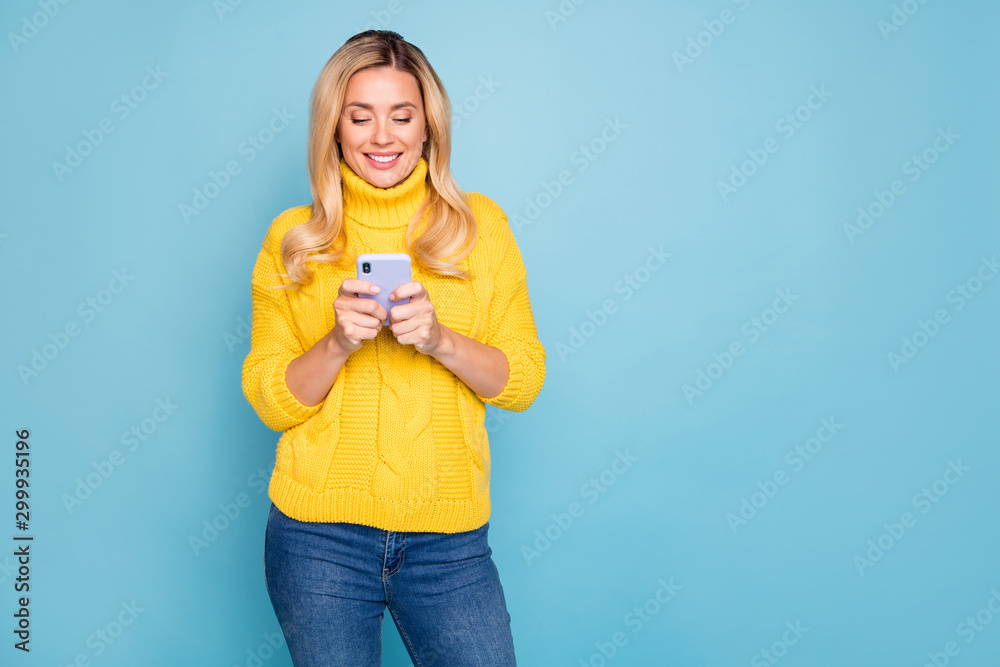Photo of amazing blond lady holding telephone hands texting comments feednews wear knitted yellow pullover jeans isolated blue color background Photo of amazing blond lady holding telephone hands texting comments feednews wear knitted yellow pullover jeans isolated blue color background