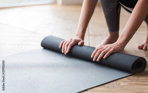 Hands of woman unrolling yoga mat before practice