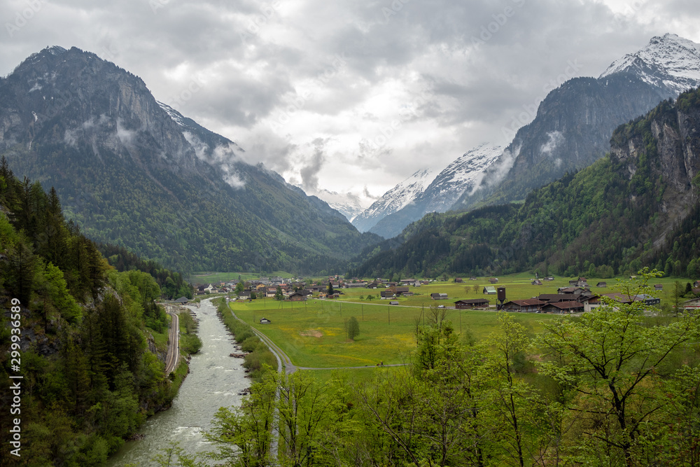 Charming panorama view of aare river, meadow and houses in small village in rural area of Switzerland on cloudy sky and mountain background with copy space