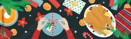 Christmas holiday dinner. Flat lay with turkey with cranberries, pumpkin pie, oranges, fir branches and gifts. Girl packing a gift.