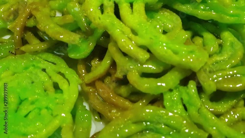 Crispy sweet Asian dessert green Jalebi cooked and served in Festival, Indian sweet street food with juicy syrup, Slow motion view. photo